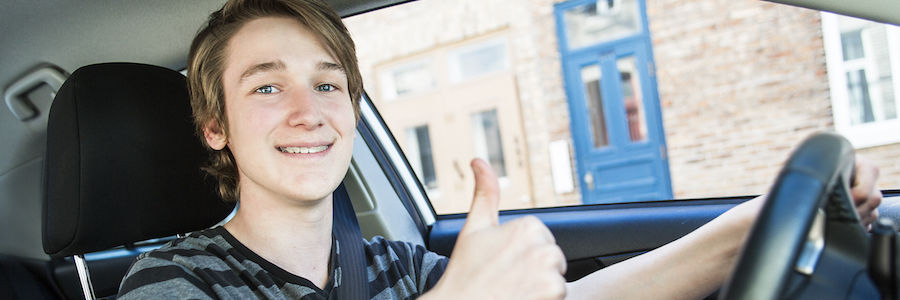 A Teenage boy and new driver behind wheel of his car