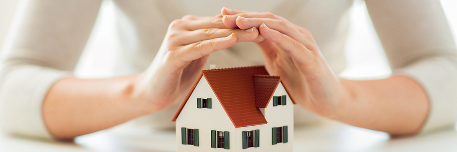 woman covering a scale model house with her hands