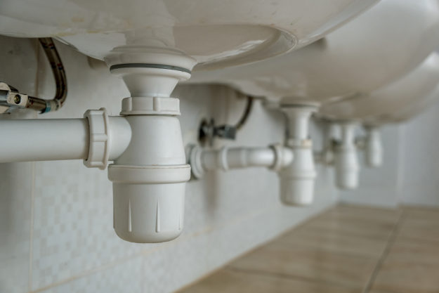 Close Up Of White Plastic Pipe Drain Under Washing Sink In Bathr