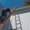 Man climbing ladder on side of house
