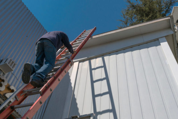 march Is Ladder Safety Month Man climbing ladder on side of house